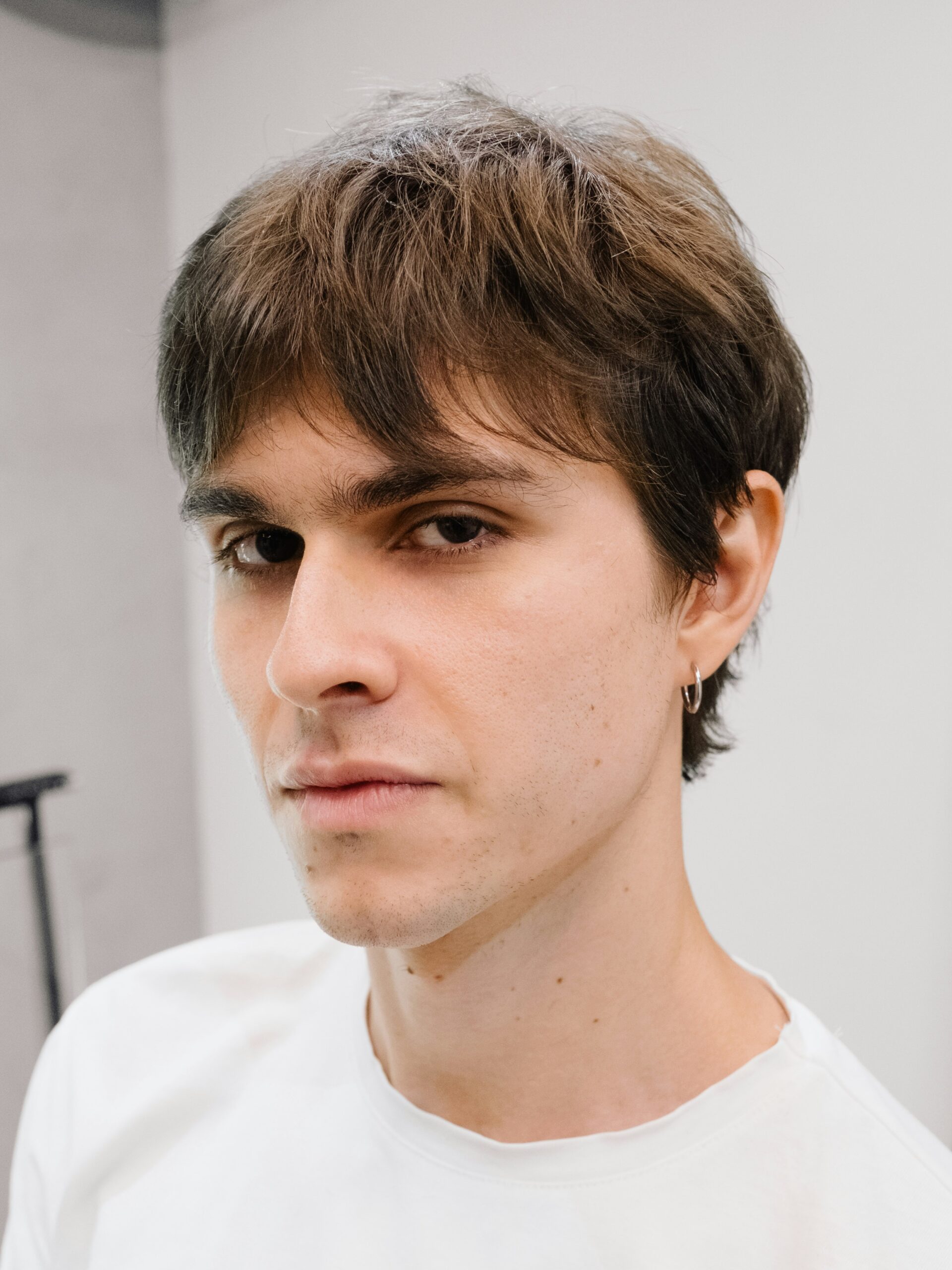 Un giovane uomo con un business mullet che indossa una t-shirt bianca.