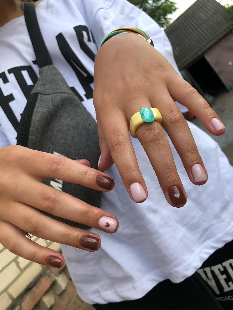 Donna con maglietta bianca all'aperto che mostra alla fotocamera la sua manicure BIAB