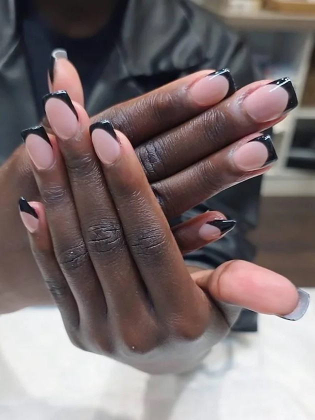 Donna in un salone di bellezza che mostra alla fotocamera la sua manicure BIAB nude con estensioni nere