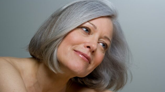 Primo piano di una donna con un caschetto grigio liscio e trucco naturale